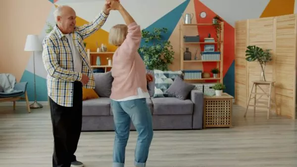 Elderly couple dancing joyfully in a living room